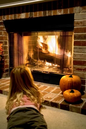 A girl laying in front of a warm fireplace