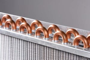 Close-up of copper evaporator coils in an air conditioner, showing heat exchange components used in HVAC systems