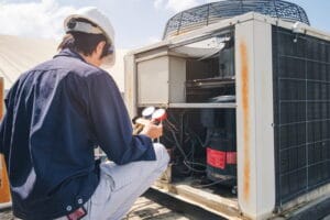 An HVAC technician checking an air conditioner