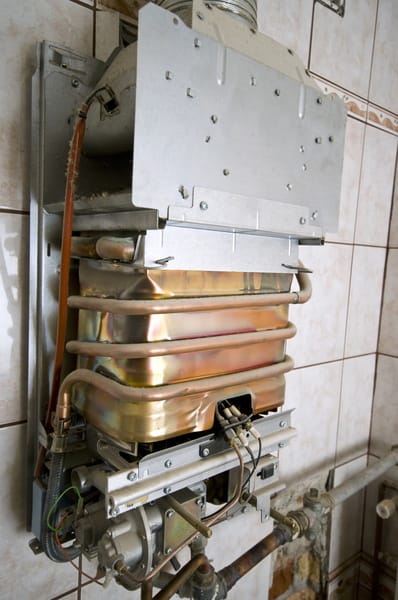 Close-up view of a wall-mounted gas boiler with exposed copper heat exchanger and internal components, showing the mechanical structure of a residential heating system