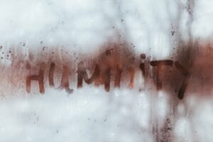 Word ‘humidity’ written on a fogged window with condensation, illustrating moisture buildup on glass