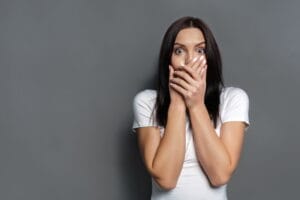 A shocked woman covering her mouth with her hands