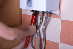 Someone repairing a tankless water heater with a wrench